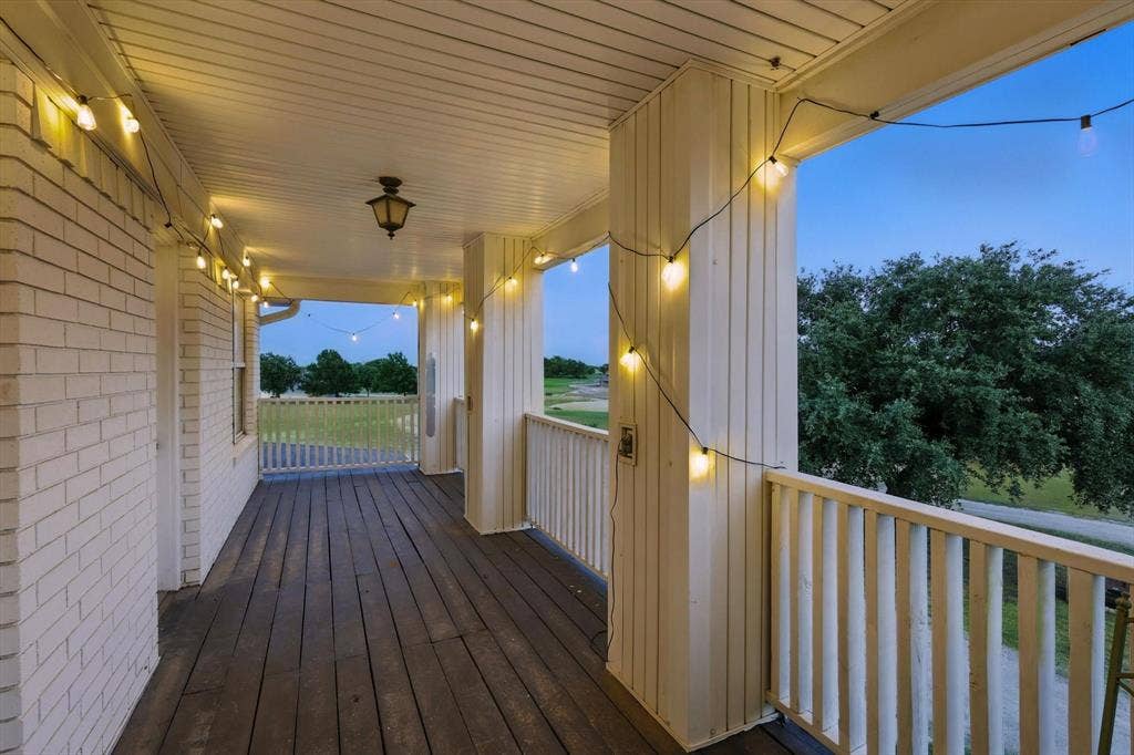 185 Quail Run Court, Decatur, TX 76234 Covered porch featuring white brick exterior, wood-finish flooring, white railing, and a mounted ceiling light fixture