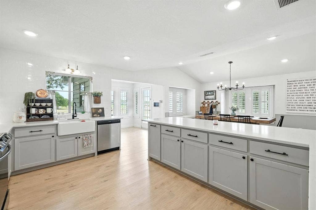 185 Quail Run Court, Decatur, TX 76234 Bright kitchen featuring a farmhouse sink, stainless steel appliances, light wood-finish flooring, and white shaker-style cabinetry with dark hardware