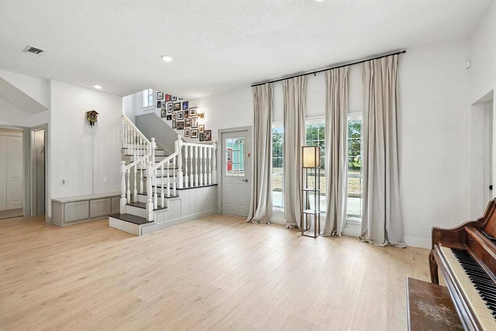 185 Quail Run Court, Decatur, TX 76234 Light wood-finish flooring, staircase with white newel posts and handrails, three tall windows, recessed lighting, and built-in storage bench