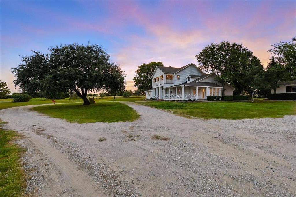 185 Quail Run Court, Decatur, TX 76234 Expansive gravel drive leading to a classic two-story residence with a wraparound porch and white exterior siding