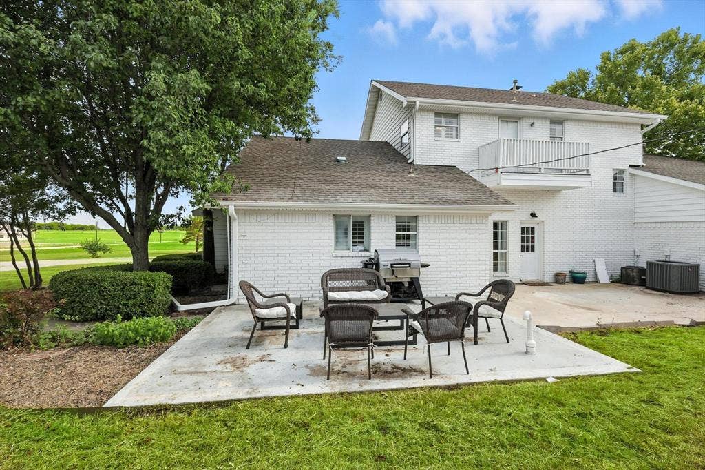 185 Quail Run Court, Decatur, TX 76234 Expansive concrete patio with a white painted brick exterior, a second-story balcony, and mature trees