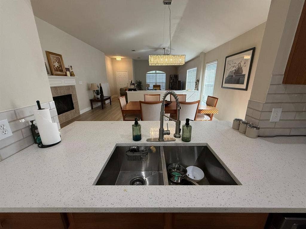 Spacious kitchen with a double basin stainless steel sink, speckled countertop, and subway tile backsplash