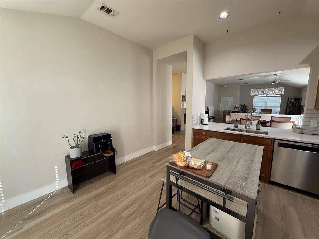 Wood-finish flooring, recessed lighting, and a kitchen featuring stainless steel appliances, a double basin sink, and a tiled backsplash