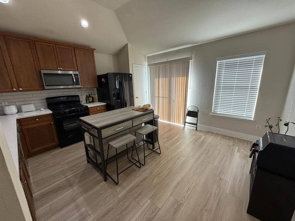 Kitchen featuring wood-finish cabinetry, white countertops, a subway tile backsplash, and stainless steel appliances