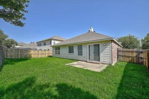 Expansive backyard featuring a manicured lawn, mature shade trees, and wooden privacy fencing
