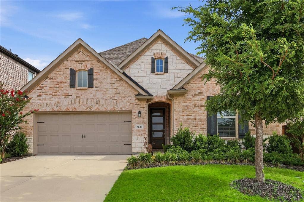 2637 Basswood Drive, Northlake, TX 76226 Brick and stone facade with dark shutters, an integrated two-car garage, and a mature tree