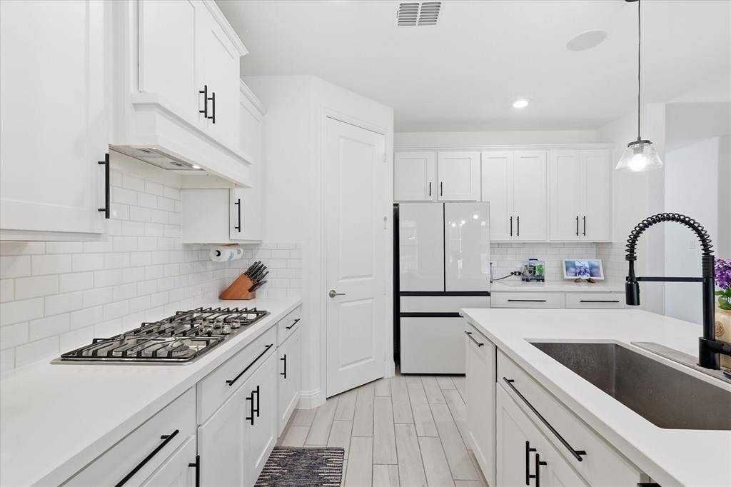 2637 Basswood Drive, Northlake, TX 76226 White shaker cabinetry with black hardware, subway tile backsplash, white countertops, built-in gas range, and wood-finish flooring