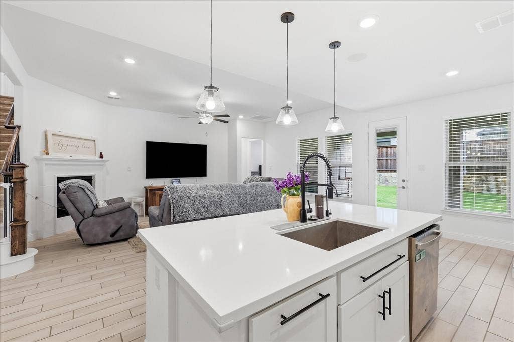 2637 Basswood Drive, Northlake, TX 76226 Kitchen island with a stainless steel sink and matte black faucet, open to a living area with a fireplace