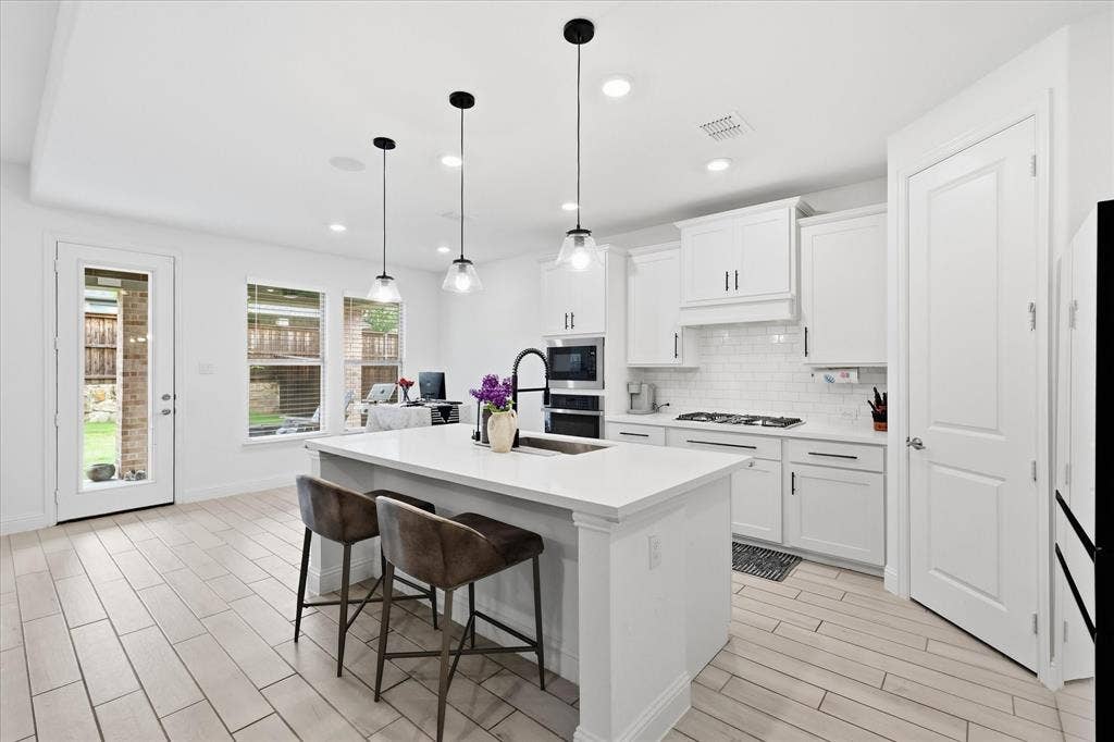 2637 Basswood Drive, Northlake, TX 76226 White cabinetry with black hardware, white subway tile backsplash, white quartz countertops, stainless steel appliances, and pendant lighting