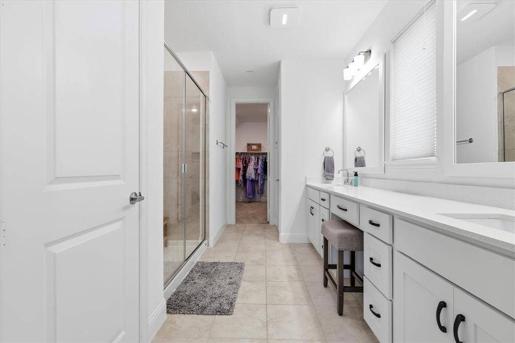 2637 Basswood Drive, Northlake, TX 76226 White shaker-style cabinetry with black hardware, stone countertop, dual undermount sinks, and a glass-enclosed shower