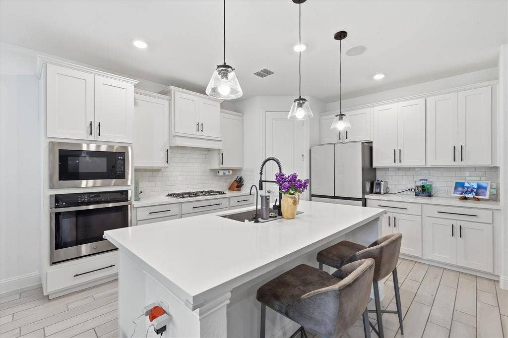 2637 Basswood Drive, Northlake, TX 76226 Kitchen featuring white shaker cabinetry, stainless steel appliances, a center island with pendant lighting, a subway tile backsplash, and light-toned wood-finish flooring