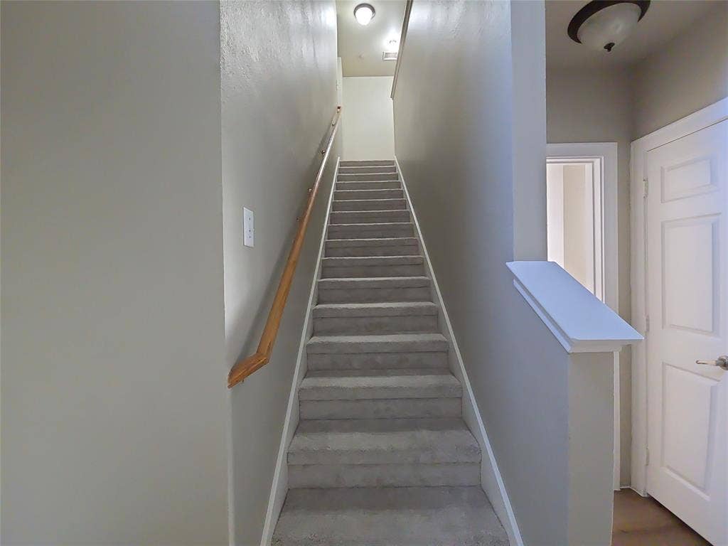 8621 Brunswick Drive, Plano, TX 75024 Carpeted staircase with a wood handrail, light gray wall finishes, and a flush-mount ceiling light