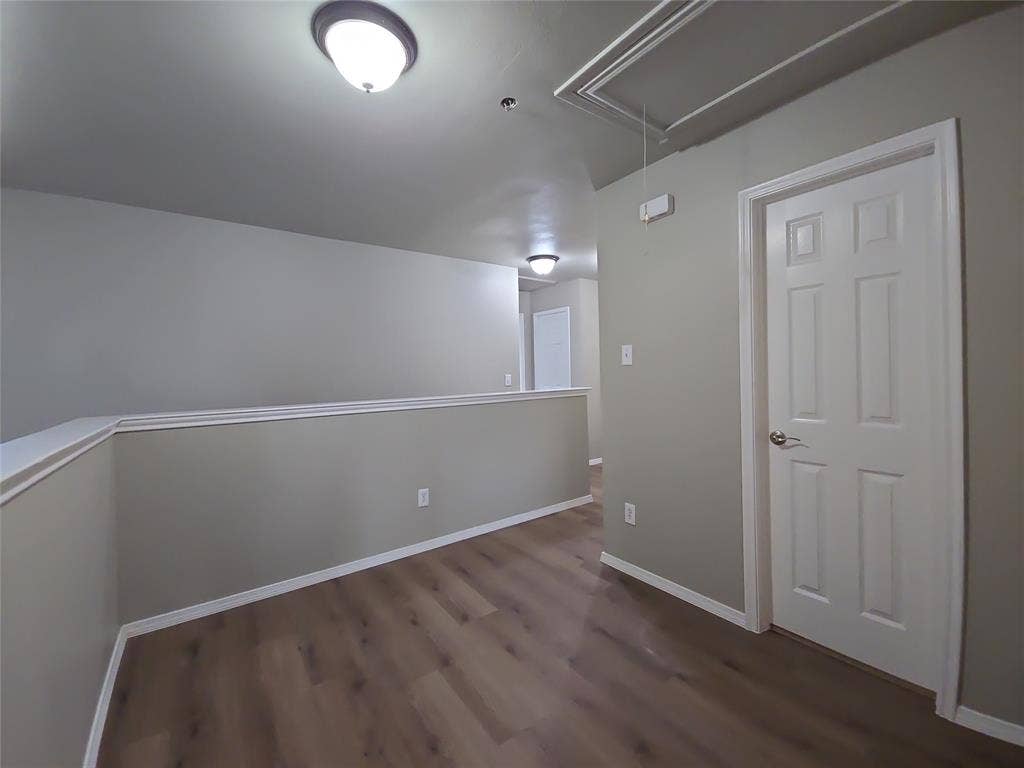 8621 Brunswick Drive, Plano, TX 75024 Wood-finish flooring, neutral wall tones, white trim, overhead flush-mount lighting, and a paneled interior door