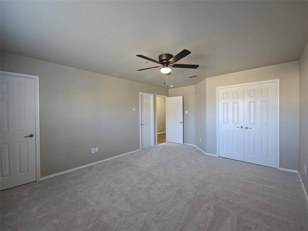 8621 Brunswick Drive, Plano, TX 75024 Neutral-toned wall paint, light-colored carpeting, multiple paneled doors, and a ceiling fan with integrated lighting
