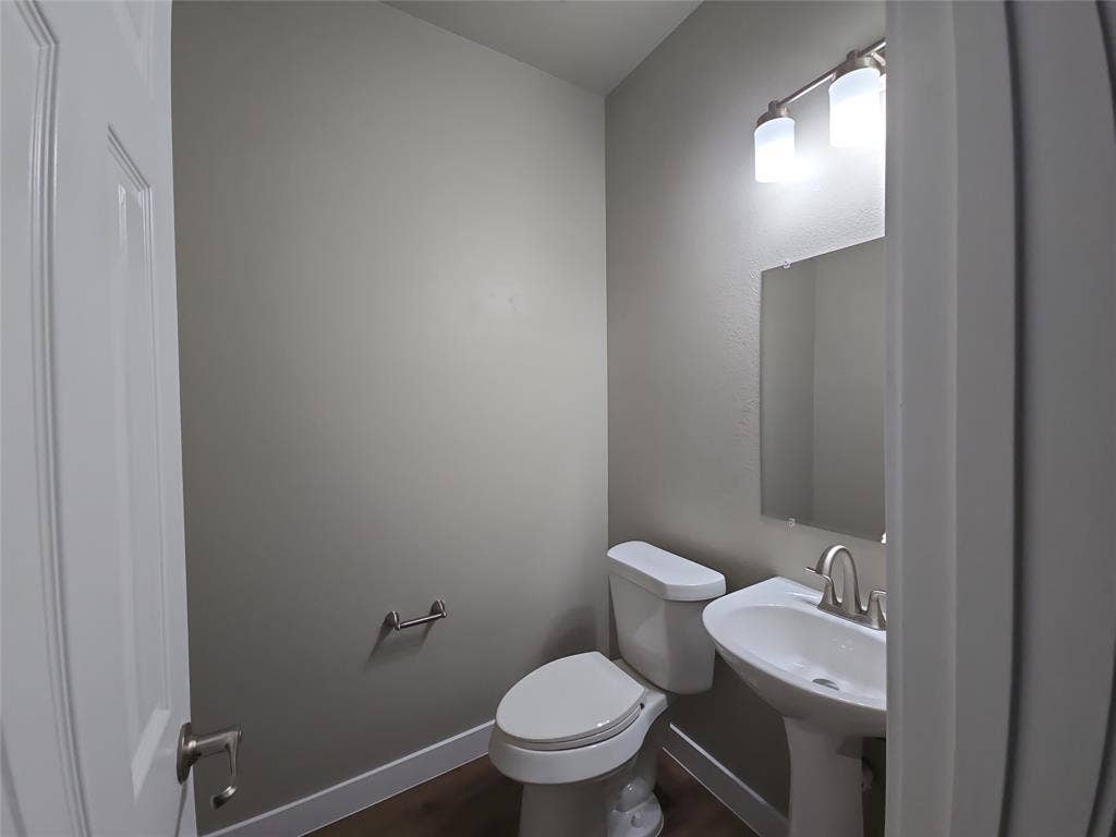8621 Brunswick Drive, Plano, TX 75024 Pedestal sink with a brushed nickel faucet, wall-mounted mirror, and overhead vanity lighting