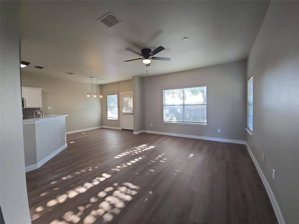 8621 Brunswick Drive, Plano, TX 75024 Wood-finish flooring throughout, vaulted ceiling with a ceiling fan, and multiple windows with blinds