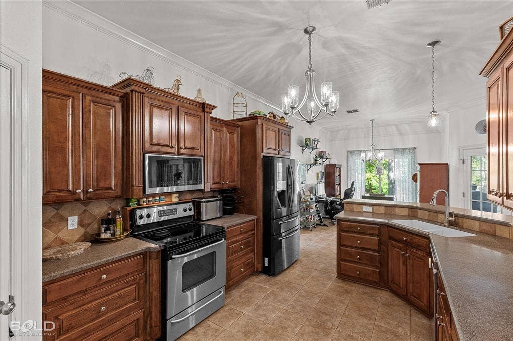 206 Silver Fox Circle, Haughton, LA 71037 Kitchen featuring stained wood cabinetry, stone-composite countertops, tile backsplash, built-in stainless steel appliances, and a central chandelier with glass shades