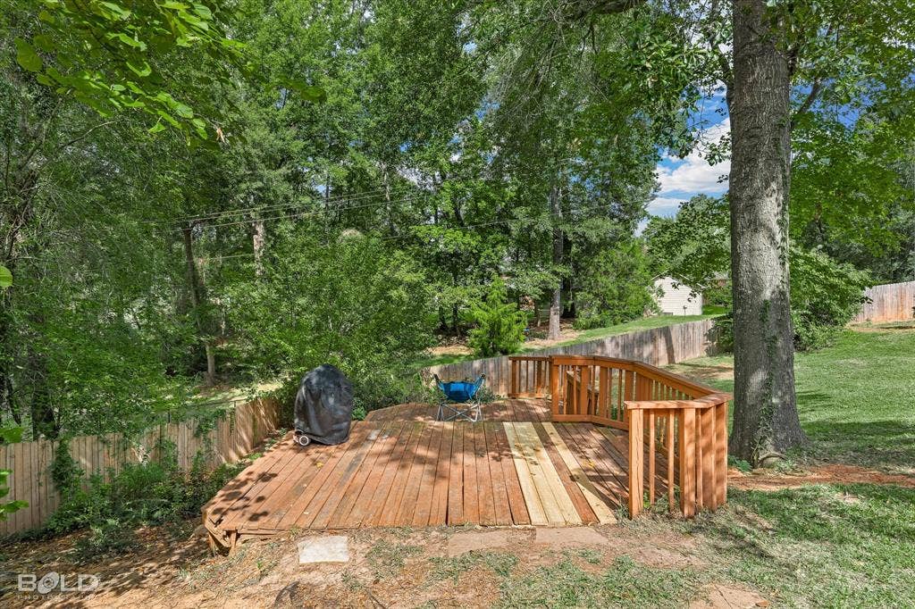 206 Silver Fox Circle, Haughton, LA 71037 Elevated wood deck featuring curved railings, enclosed by a wood privacy fence and mature trees