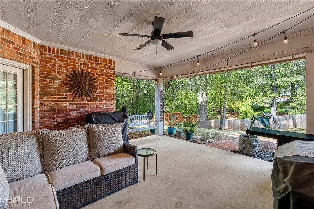 206 Silver Fox Circle, Haughton, LA 71037 Covered patio featuring exposed brick masonry, concrete flooring, a ceiling-mounted fan, and string lighting