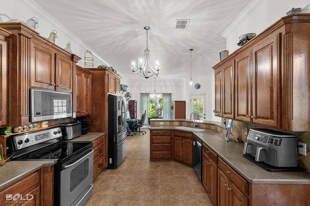 206 Silver Fox Circle, Haughton, LA 71037 Kitchen featuring stained wood cabinetry, stone-composite countertops, tile flooring, stainless steel appliances, and a multi-arm chandelier