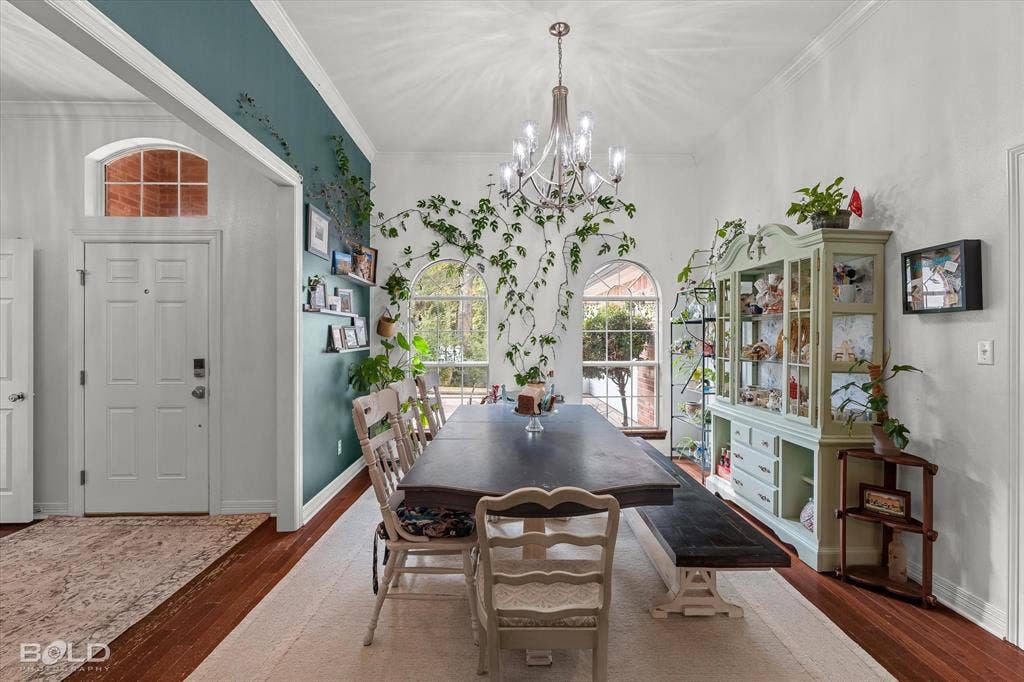 206 Silver Fox Circle, Haughton, LA 71037 Dining area featuring wood-finish flooring, high ceilings with an ornate multi-arm chandelier, arched windows, and crown molding