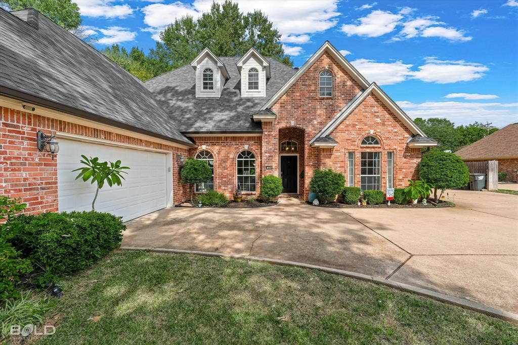 206 Silver Fox Circle, Haughton, LA 71037 Traditional brick exterior featuring a multi-gable roofline, arched window detailing, dual roof dormers, and an attached multi-car garage