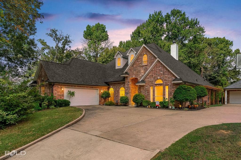 206 Silver Fox Circle, Haughton, LA 71037 Multi-gabled brick exterior featuring arched windows, a multi-car garage, and an expansive concrete driveway