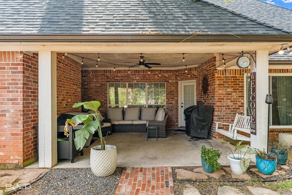 206 Silver Fox Circle, Haughton, LA 71037 Covered patio featuring red brick exterior walls, a concrete floor, an integrated ceiling fan, and string lighting