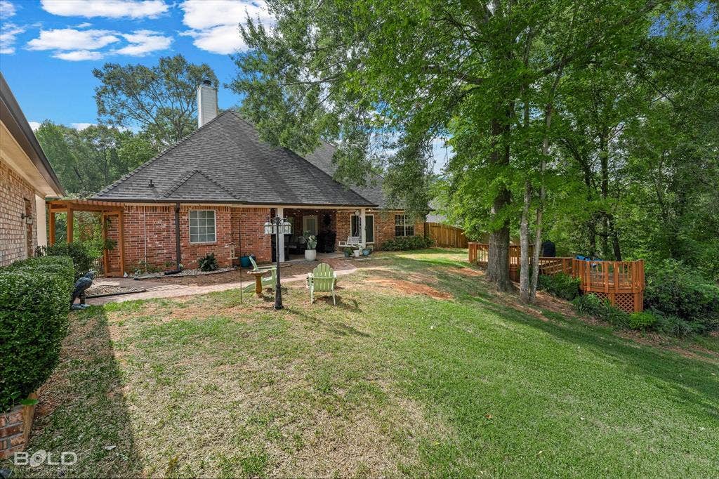 206 Silver Fox Circle, Haughton, LA 71037 Brick exterior with a covered rear patio, multi-level wood deck, and mature trees