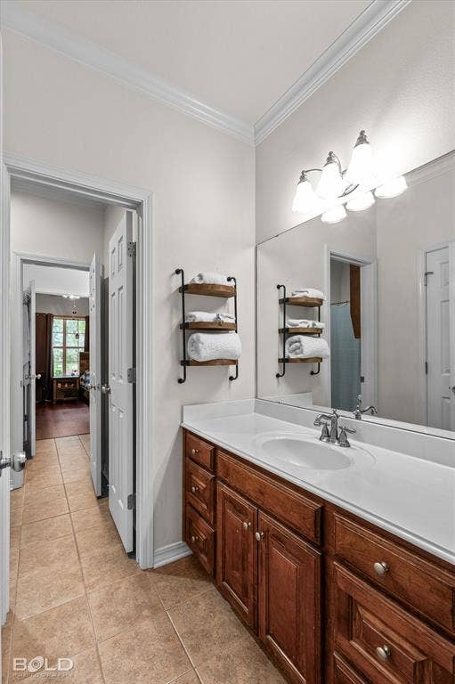 206 Silver Fox Circle, Haughton, LA 71037 Vanity featuring rich wood cabinetry, integrated sink, large frameless mirror, and multi-bulb overhead lighting, complemented by tile flooring and crown molding