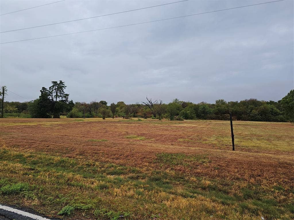 1105 I-45, Ennis, TX 75119 Expansive, undeveloped land with a distant tree line and overhead utility lines