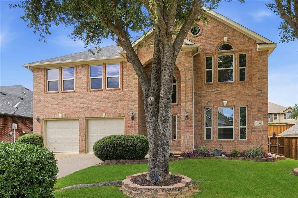 Brick exterior with arched entryways, multiple windows, and a two-car garage