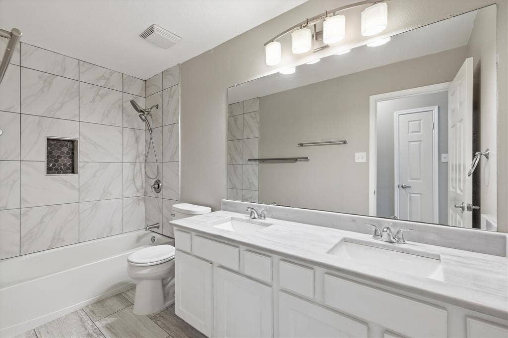Dual vanity with undermount sinks, stone countertops, and chrome fixtures