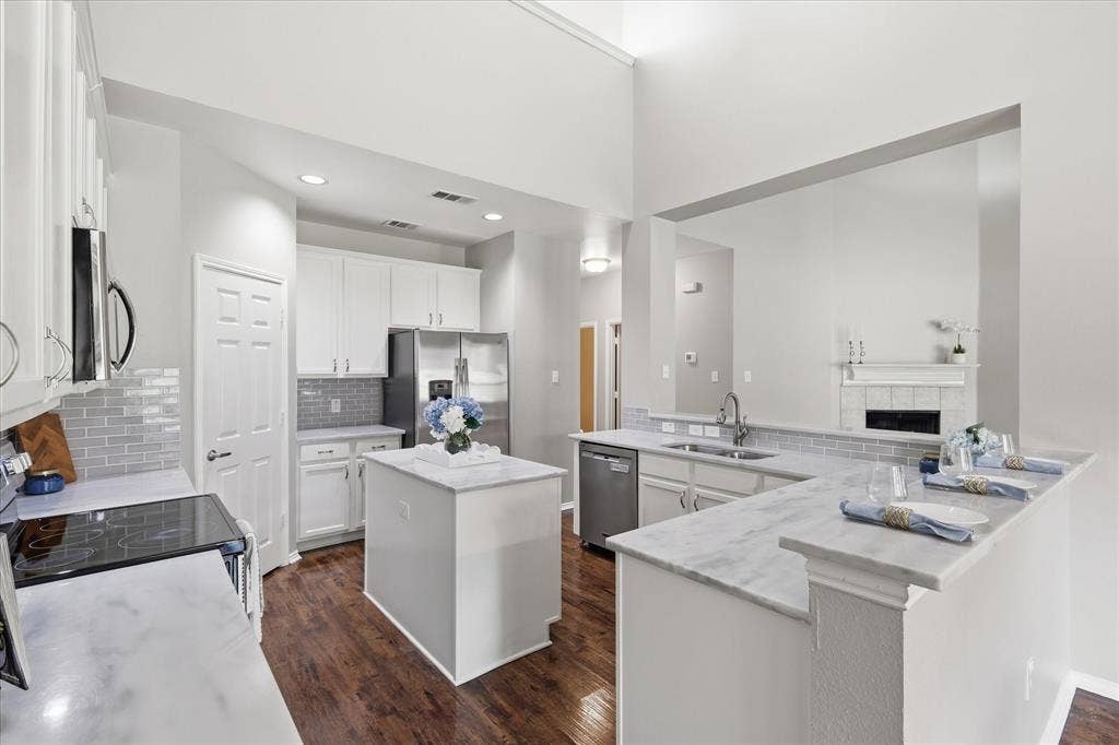 Kitchen featuring wood-finish flooring, white cabinetry, a center island with countertop, and stainless steel appliances