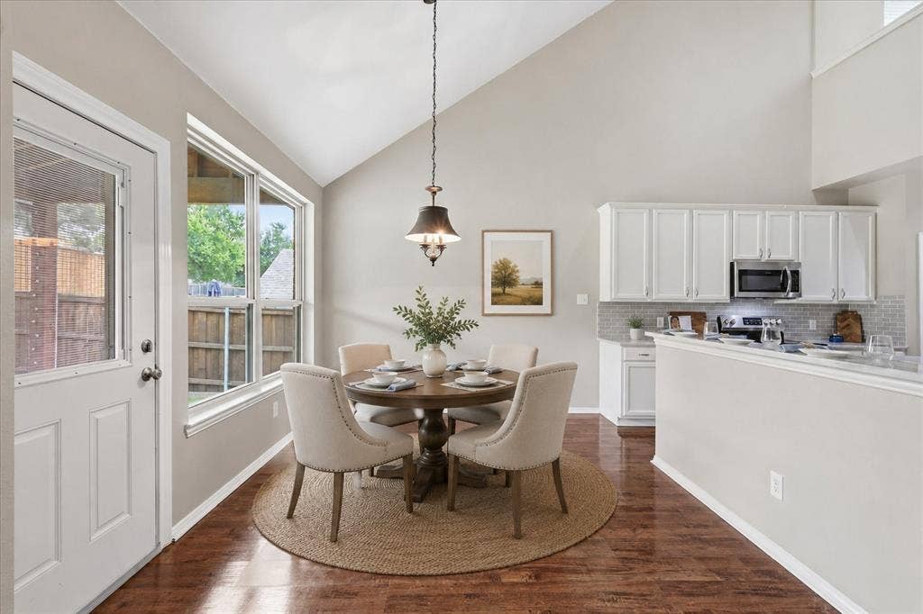 Open-concept dining area with vaulted ceilings, wood-finish flooring, and natural light from expansive windows