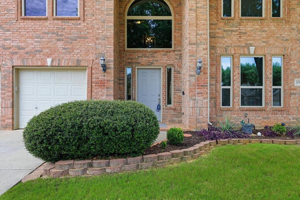 Brick exterior featuring an arched window, transom window, and a paneled garage door