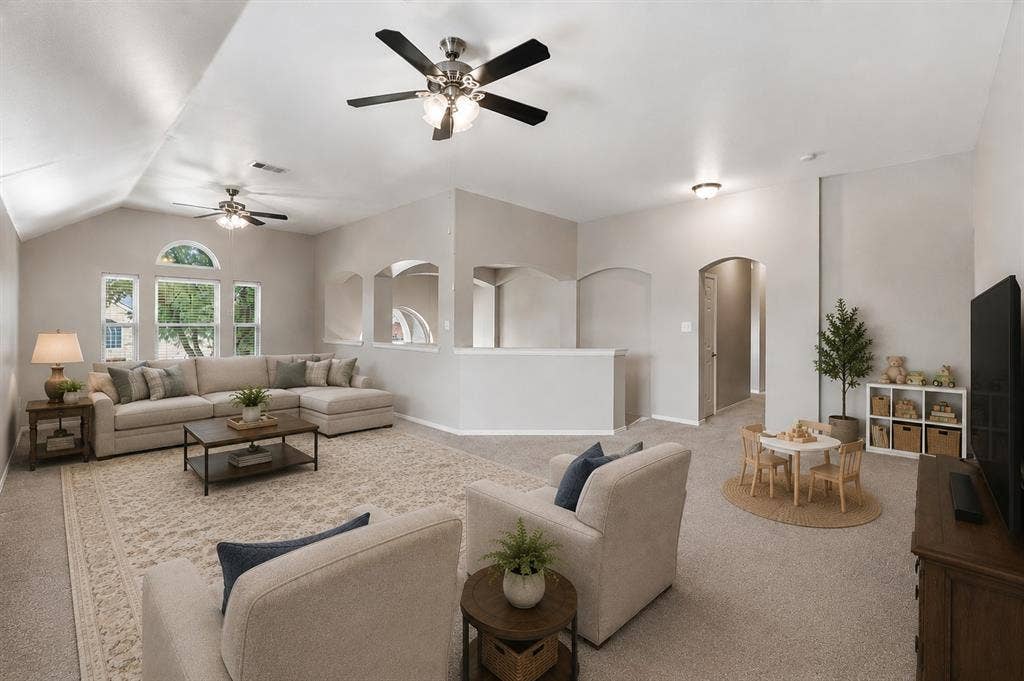 Vaulted ceilings with ceiling fans, arched window, carpeted flooring, and architectural archways