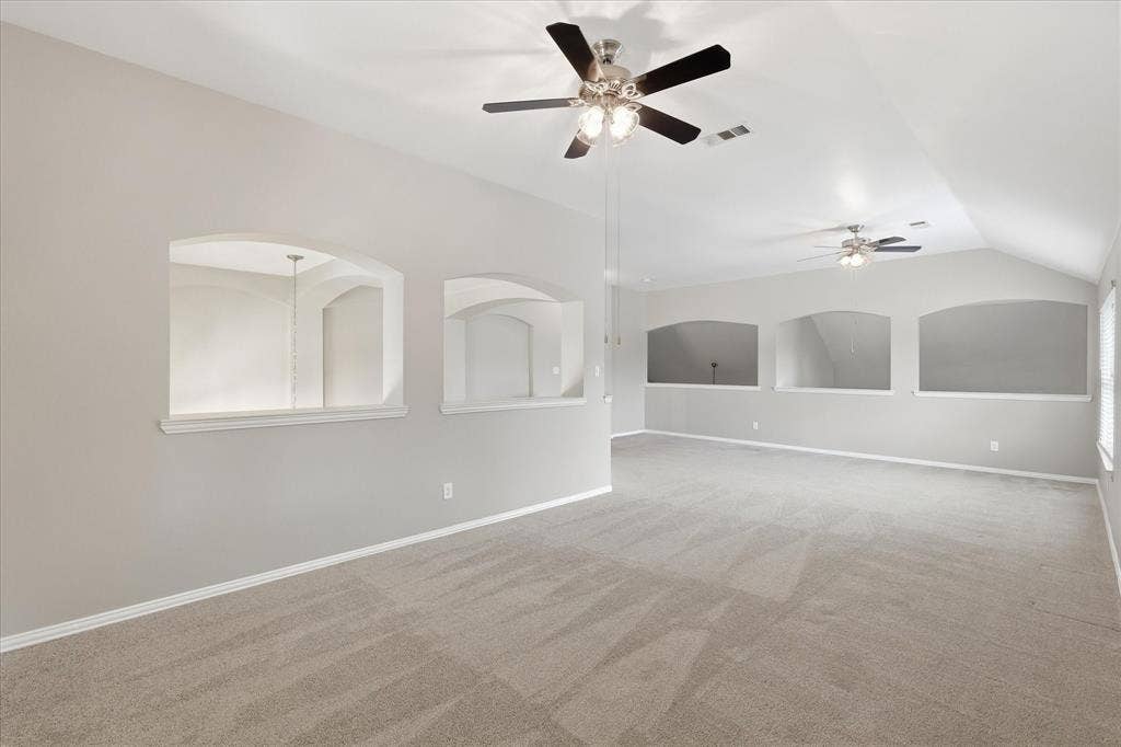 Expansive room with vaulted ceilings, recessed wall niches, and neutral carpeting