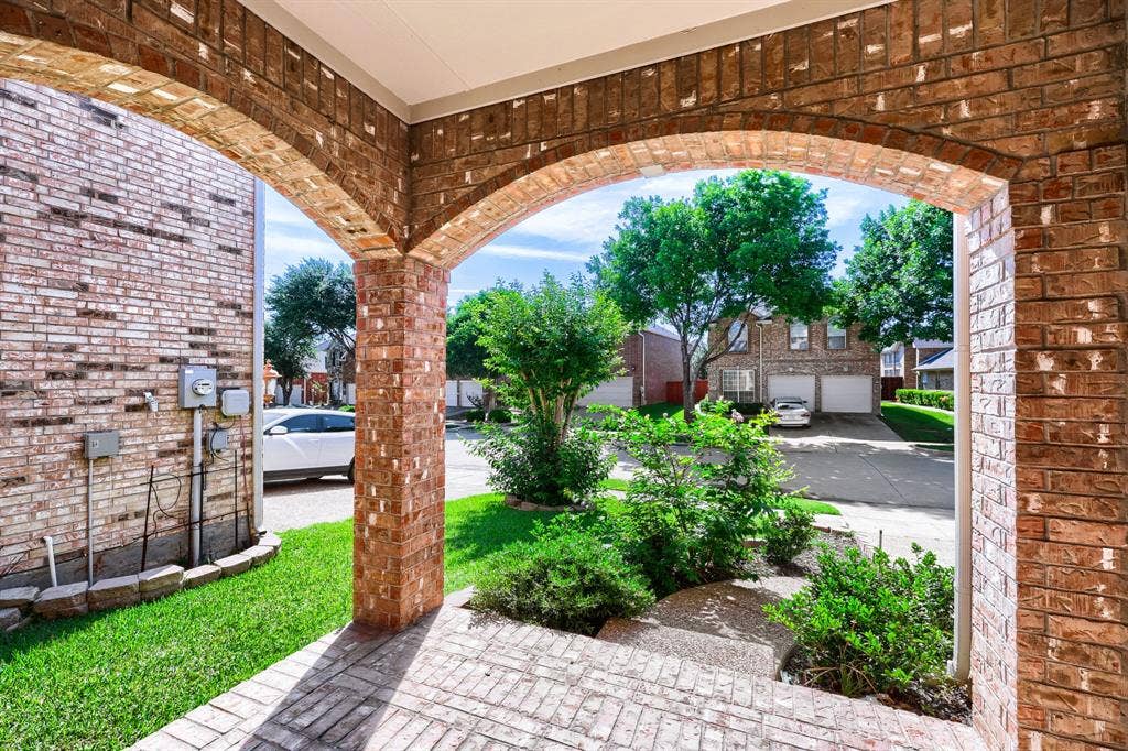 8115 Dogwood Lane, Irving, TX 75063 Brick archways and columns, brick flooring, landscaped shrubbery, and a manicured lawn