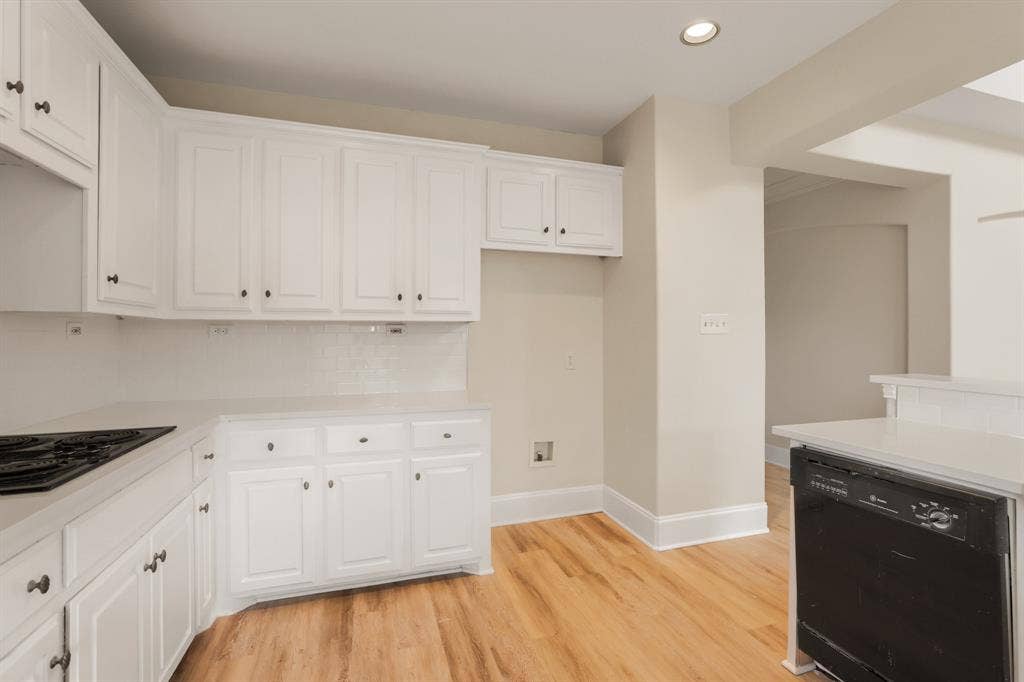 8115 Dogwood Lane, Irving, TX 75063 White cabinetry, light-toned wood-finish flooring, recessed lighting, white subway tile backsplash, and a built-in cooktop