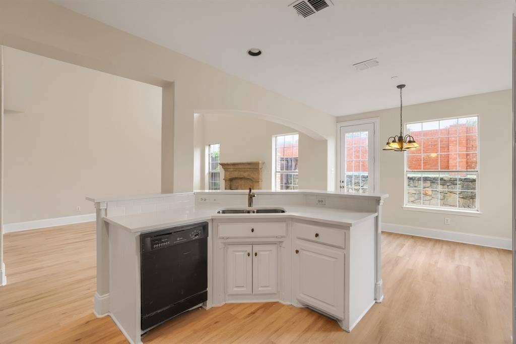 8115 Dogwood Lane, Irving, TX 75063 Kitchen island featuring a dual-basin sink, white cabinetry, and a built-in dishwasher