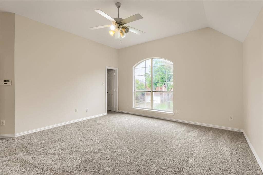 8115 Dogwood Lane, Irving, TX 75063 Arched window, vaulted ceiling, ceiling fan with integrated lighting, wall-to-wall carpeting, and light-toned walls