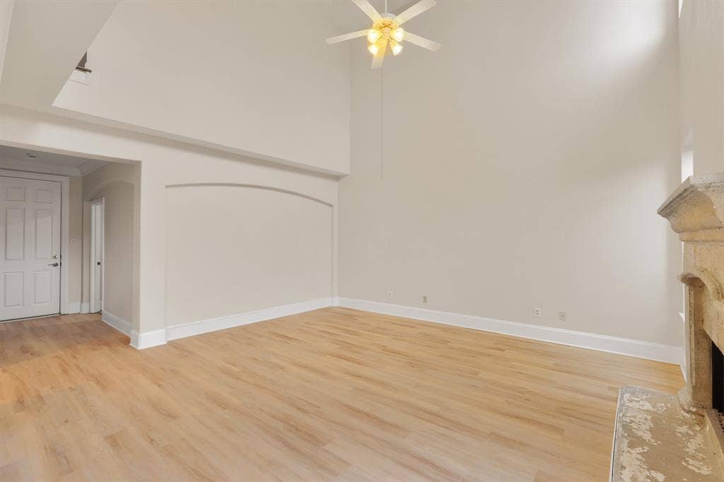 8115 Dogwood Lane, Irving, TX 75063 Vaulted ceiling with a ceiling fan, wood-finish flooring, stone-clad fireplace, and an arched wall detail