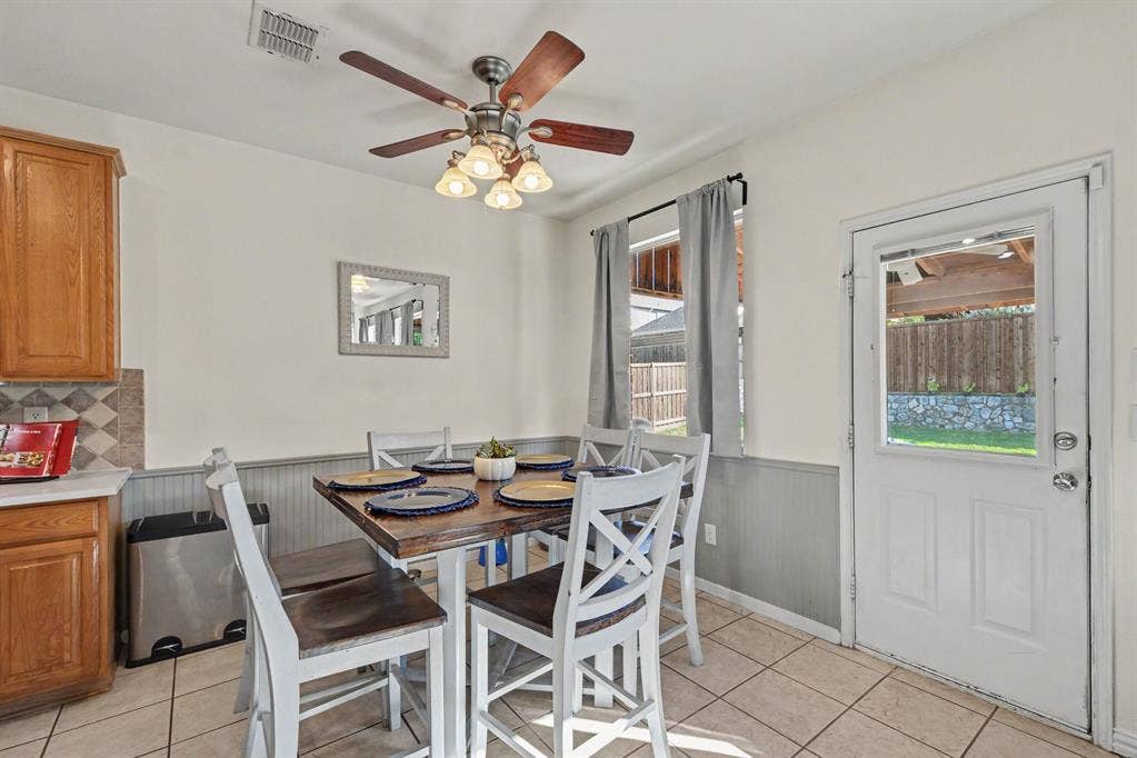 6509 Cartier Court, McKinney, TX 75072 Tiled flooring, warm wood-finish cabinetry, patterned backsplash, ceiling fan with integrated lighting, and a glass-paneled exterior door