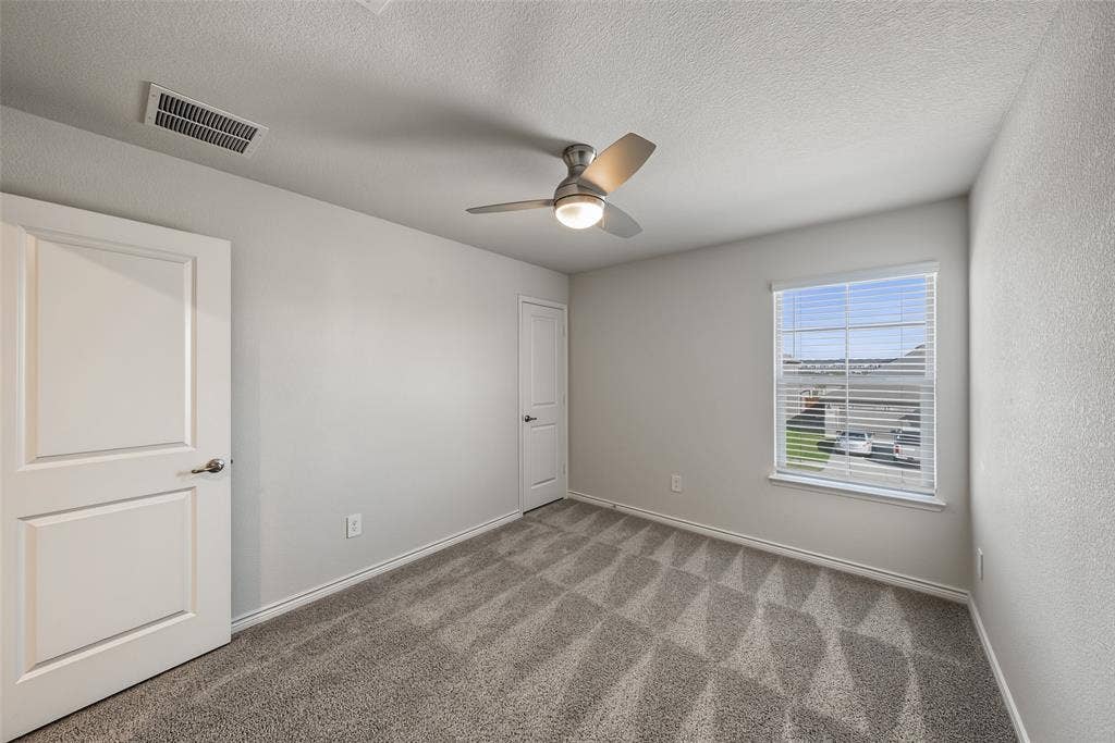 Neutral-toned room, carpet flooring, a ceiling fan with integrated lighting, and a window with blinds