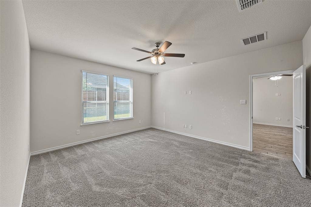 Plush grey carpeting with a ceiling fan and overhead lighting