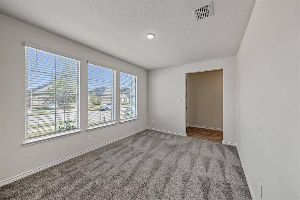 Recessed lighting, three large windows with blinds, patterned carpet flooring, and a wood-finish floor entryway