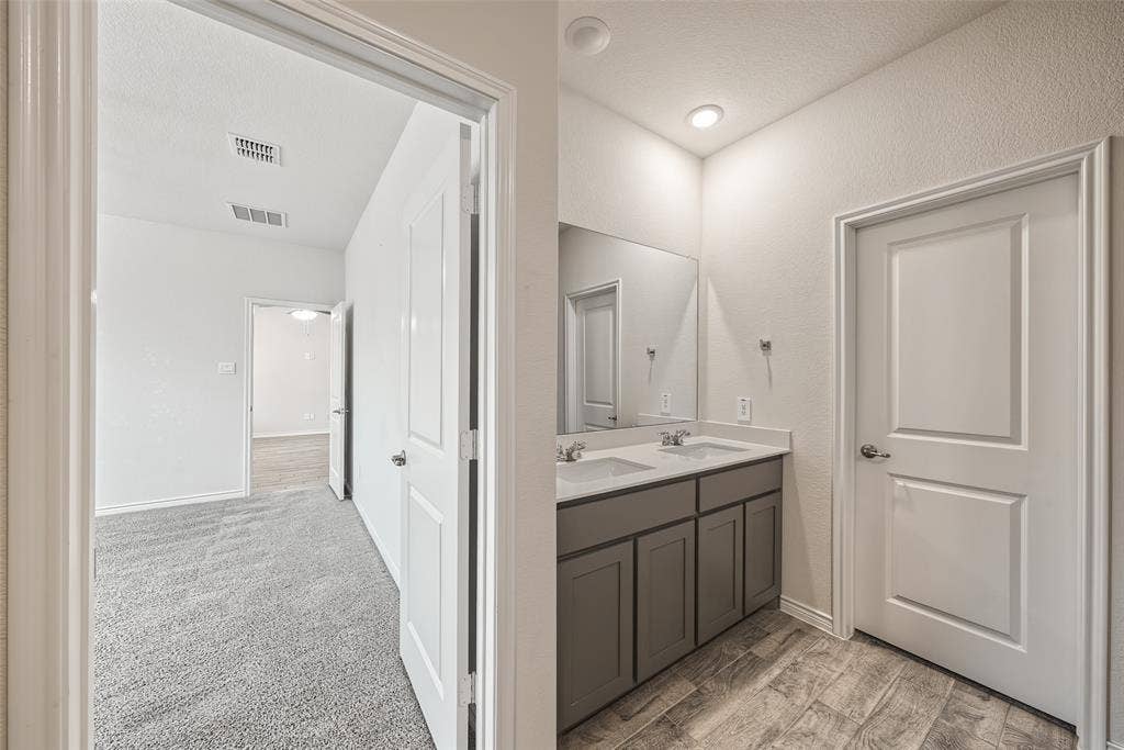 Dual vanity with undermount sinks, porcelain tile flooring, and recessed lighting