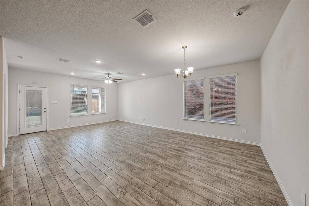 Spacious open-concept living area featuring porcelain tile flooring throughout, recessed lighting, ceiling fan, and large windows framed with brick exterior views