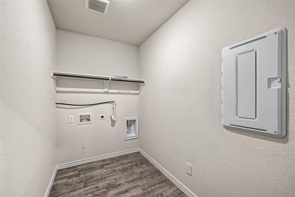 This utility space is located downstairs by the kitchen with porcelain tile flooring, a wall-mounted shelf, and appliance connections